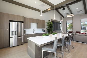 Clubroom kitchen with a large island and grey chairs.